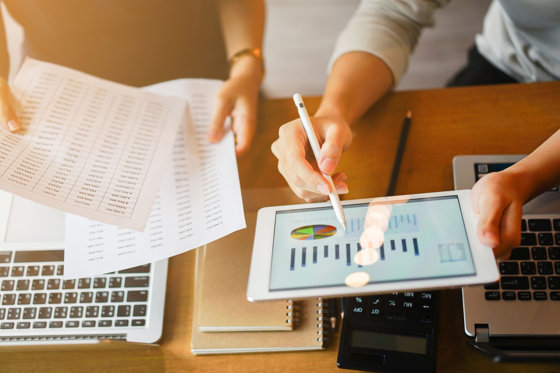 close up group of businessman use stylus pen for explaining dashboard about company's profit monthly on tablet and businesswoman holding report paper for collaborate  work at meeting event , business finance concept